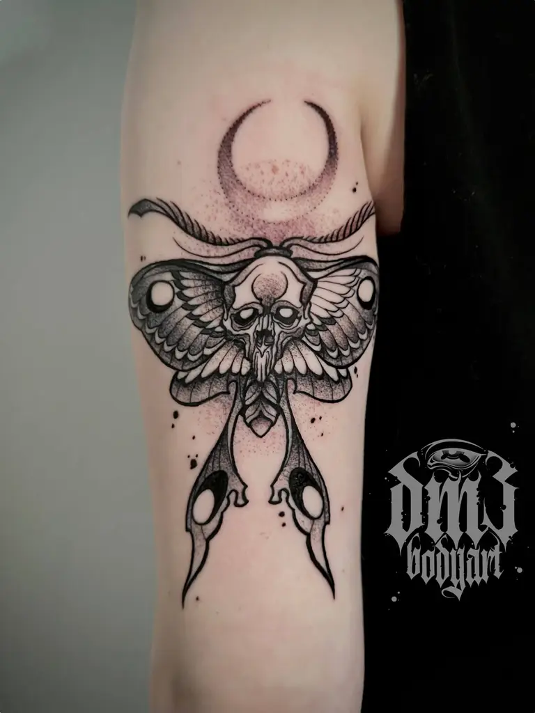 Detailreiches Blackwork Tattoo einer kunstvollen Motte mit Mondsichel auf dem Oberarm, gestochen im DM3 Bodyart Studio in Würzburg. Feine Linien, präzise Schattierungen und individueller illustrativer Stil im Dark-Art Look. Custom Tattoo mit einzigartigem Design für Tattoo-Liebhaber, die hochwertige Körperkunst suchen. Professionelles Tattoo-Studio in Würzburg – spezialisiert auf Blackwork, Dark-Art und illustrative Tattoos.