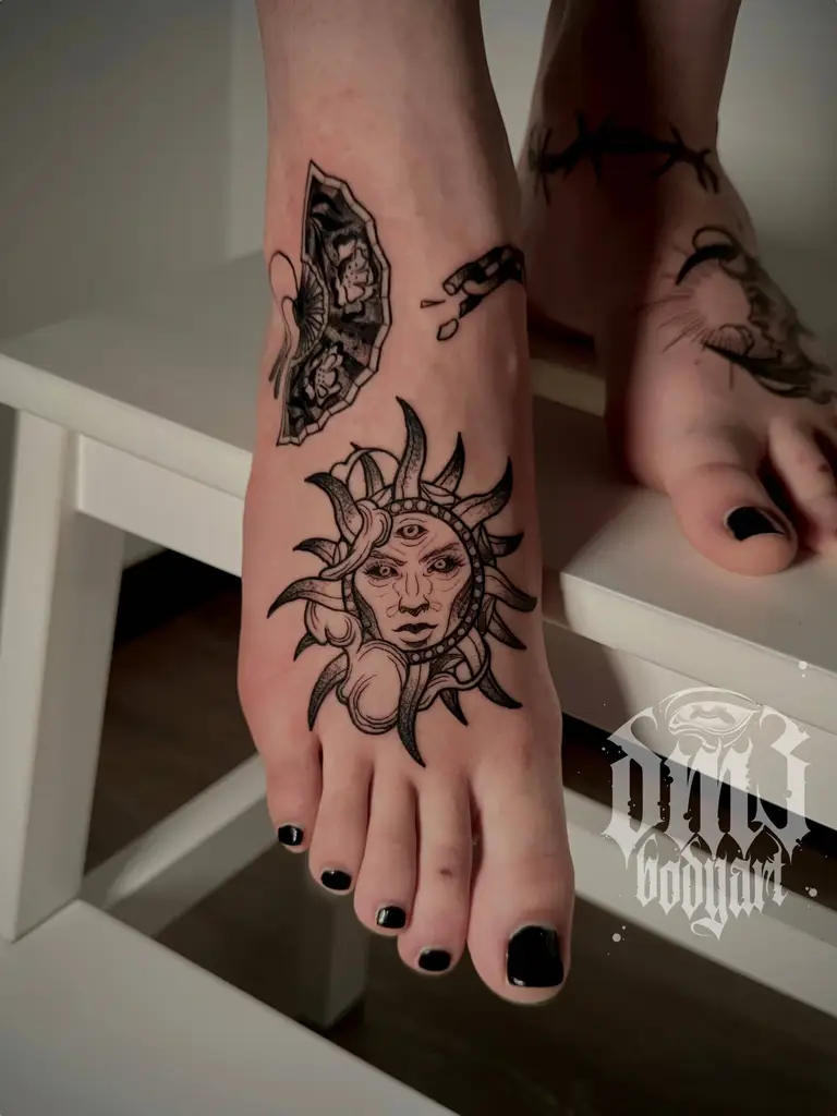 Detailreiche kleine Black-And-Grey Illustrative-Tattoos von mehreren Motiven, wie Sonne, Mond, Stacheldraht, Vasen und Fächer auf den Füßen, gestochen im DM3 Bodyart Studio in Würzburg. Feine Linien, präzise Schattierungen und individueller illustrativer Stil im Dark-Art Look. Custom Tattoo mit einzigartigem Design für Tattoo-Liebhaber, die hochwertige Körperkunst suchen. Professionelles Tattoo-Studio in Würzburg – spezialisiert auf Blackwork, Dark-Art und illustrative Tattoos.