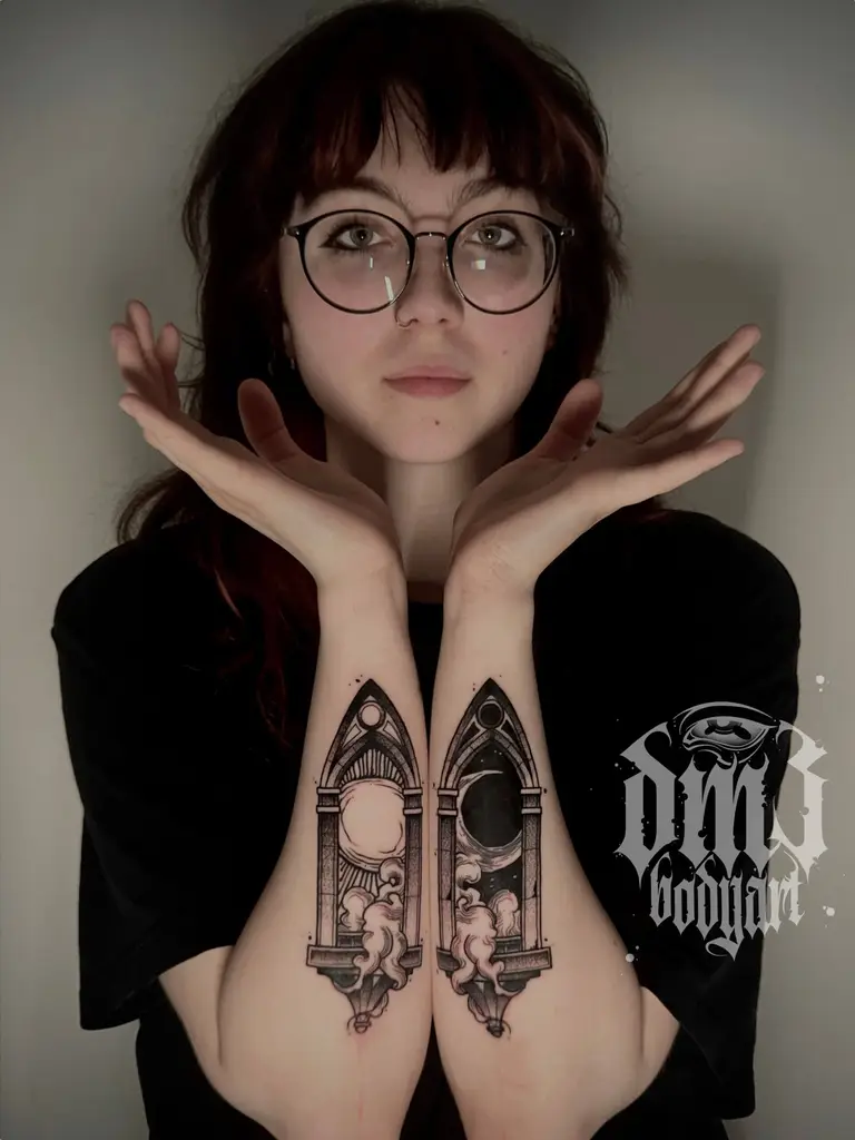 Detailreiche Blackwork Tattoos von zwei Kathedralenfenster mit Sonnen- und Mond-Motiv und kleiner Landschaft auf den Unterarmen, gestochen im DM3 Bodyart Studio in Würzburg. Feine Linien, präzise Schattierungen und individueller illustrativer Stil im Dark-Art Look. Custom Tattoo mit einzigartigem Design für Tattoo-Liebhaber, die hochwertige Körperkunst suchen. Professionelles Tattoo-Studio in Würzburg – spezialisiert auf Blackwork, Dark-Art und illustrative Tattoos.