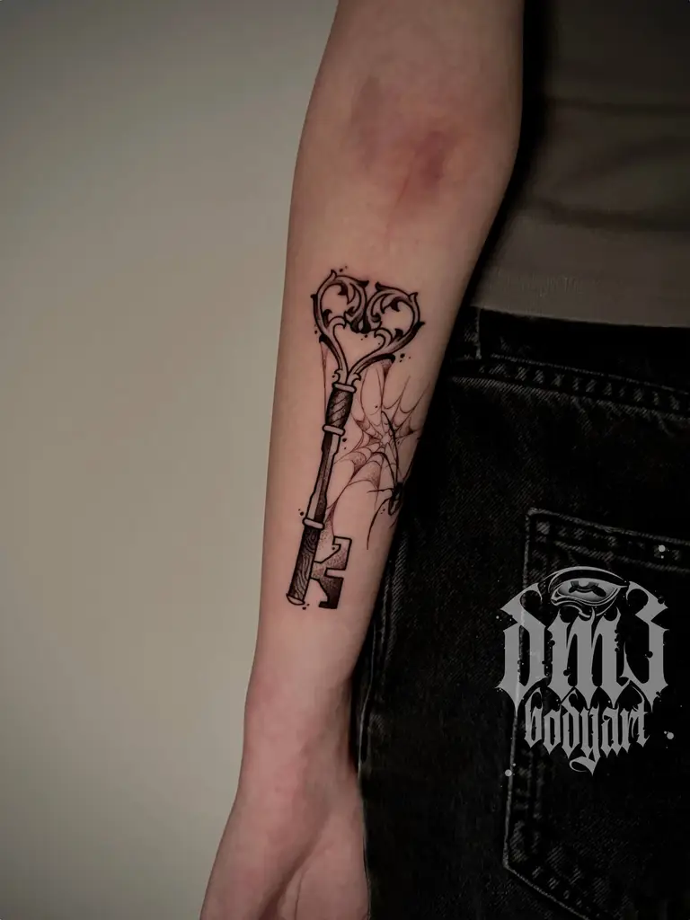 Kleines Blackwork Tattoo eines detailreichen Schlüssels mit Spinnenweben und Spinne am Unterarm, gestochen im DM3 Bodyart Studio in Würzburg. Feine Linien, präzise Schattierungen und individueller illustrativer Stil im Dark-Art Look. Custom Tattoo mit einzigartigem Design für Tattoo-Liebhaber, die hochwertige Körperkunst suchen. Professionelles Tattoo-Studio in Würzburg – spezialisiert auf Blackwork, Dark-Art und illustrative Tattoos.